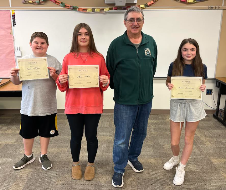 Carter, Alyssa, and Arianna hold their certificates while posing for a photo with Larry.